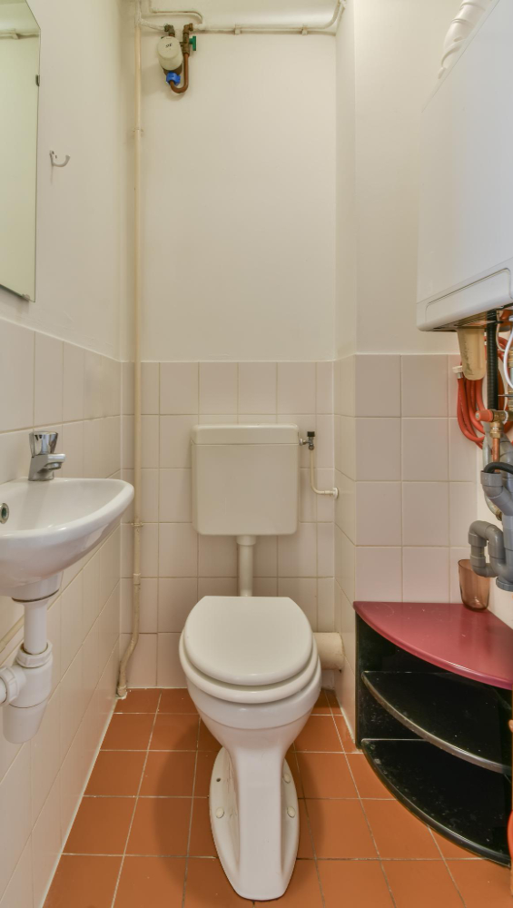 Inodoro instalado en baño con tuberías y conexiones de plomería visibles